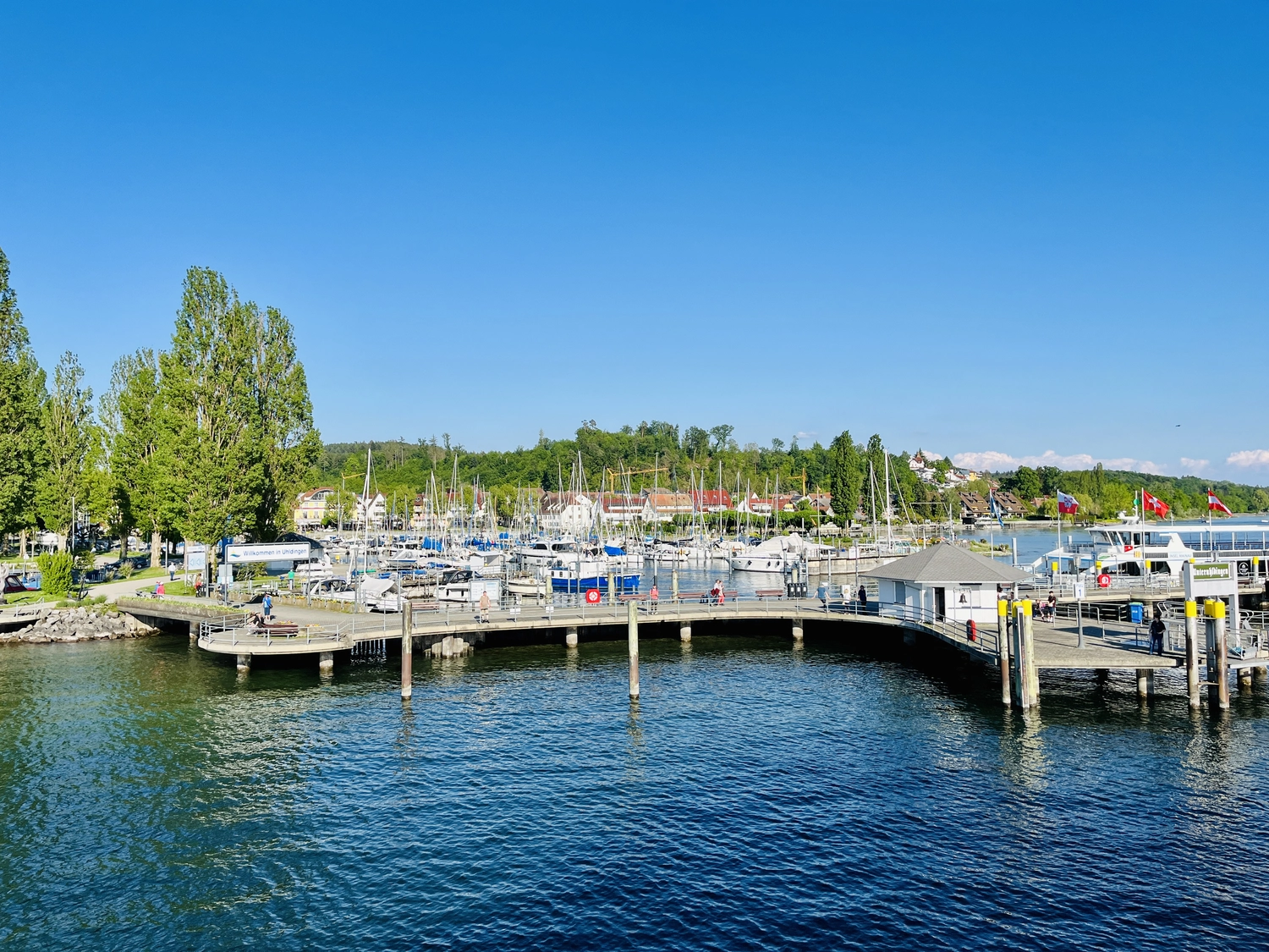 Holzbrücke über Wasser mit Hütten am Ufer in Uhldingen Mühlhofen, ideal für Luxus-Ferienwohnungen am Bodensee.